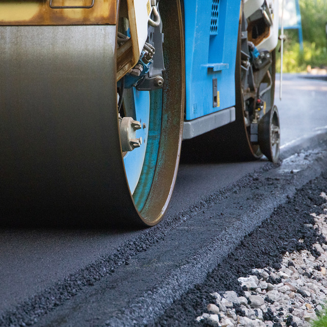 De rand van een weg die wordt geasfalteerd door een blauwe machine
